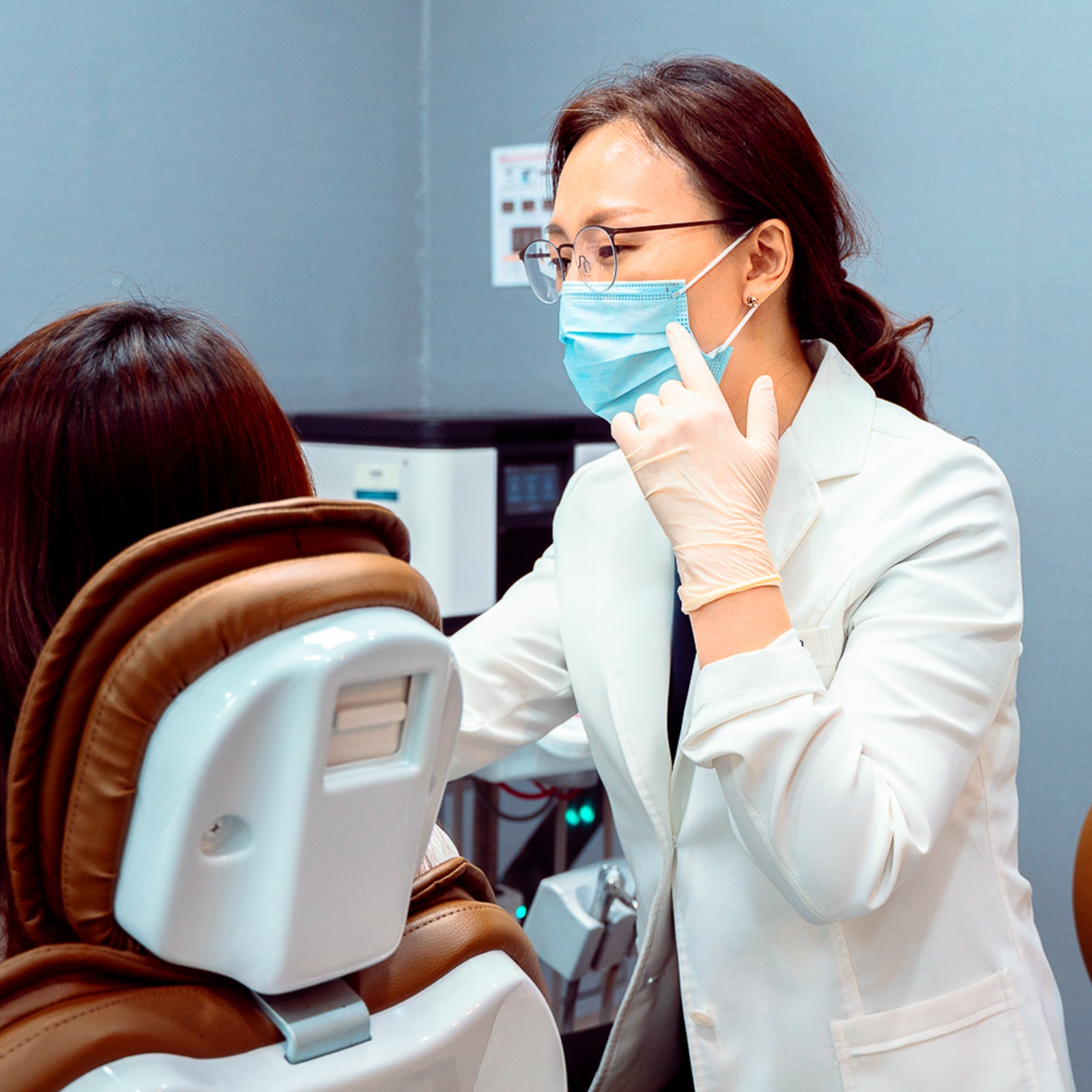 마스크를 쓴 원장이 진료 의자에 앉은 환자를 마주 보고 손짓하며 설명하고 있다